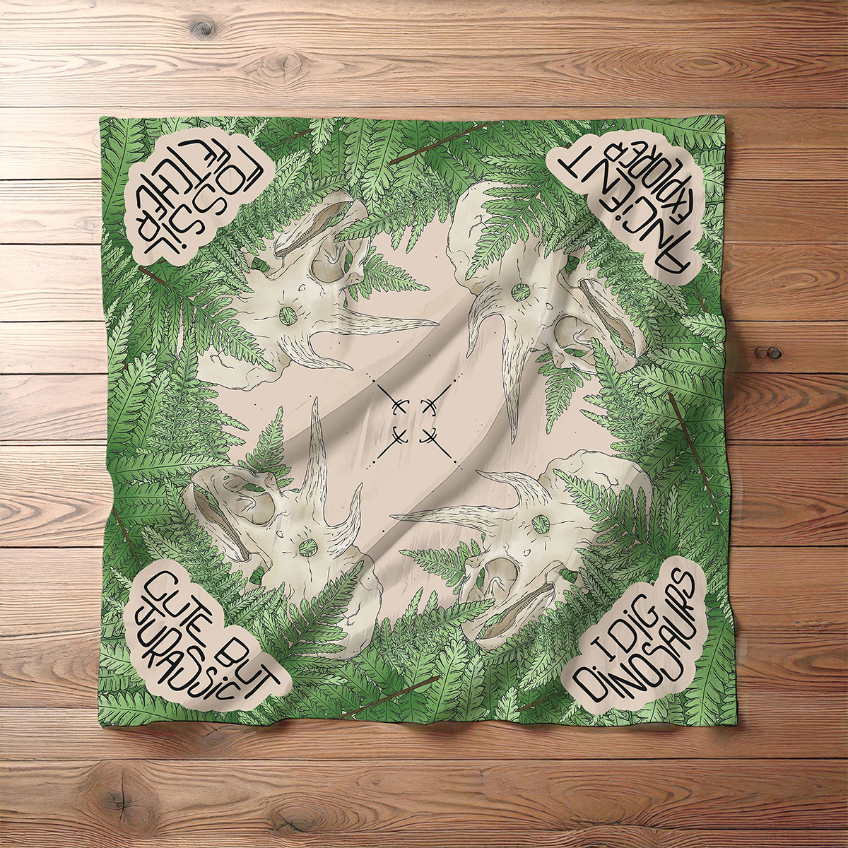 Full bandane with dinosaur and foliage design on a wooden surface.