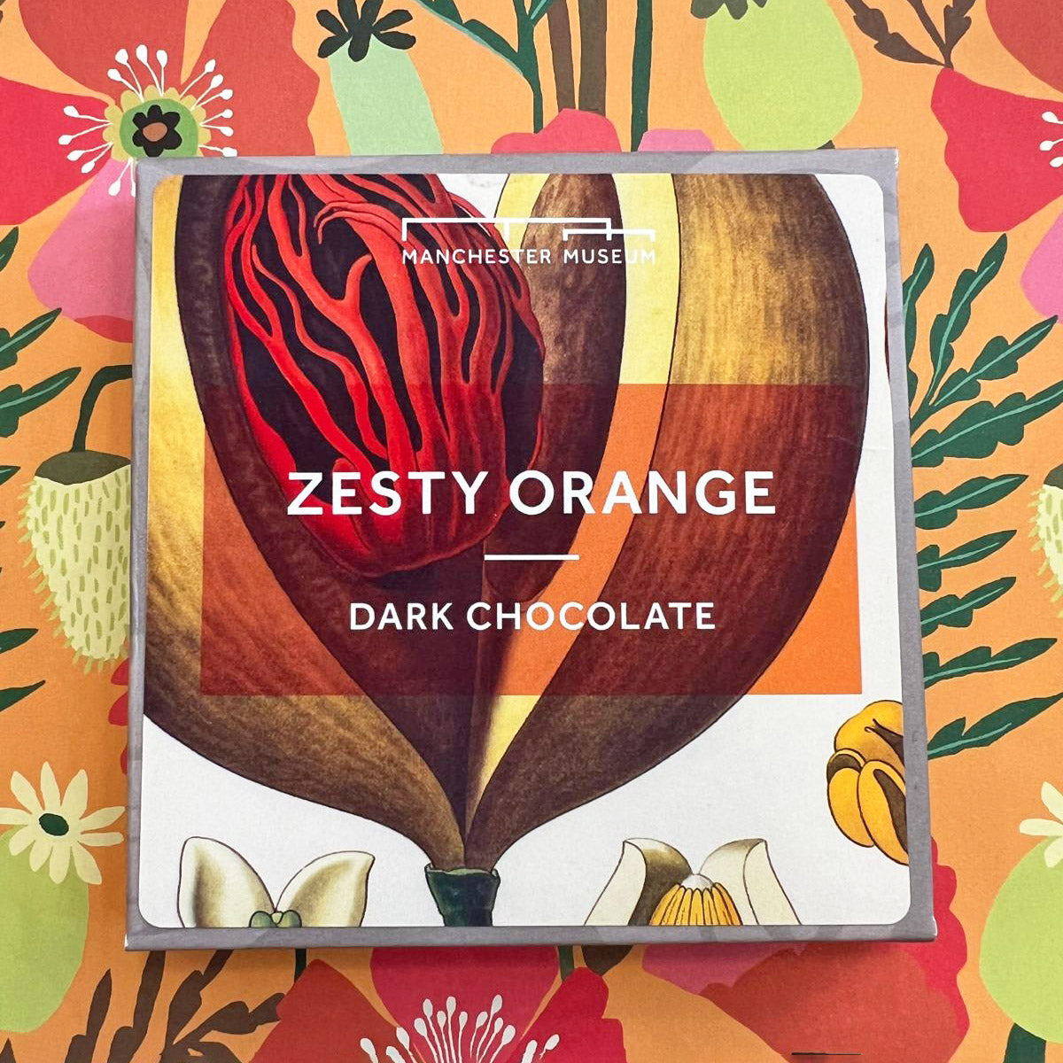 Packaging for Zesty orange chocolate with a large botanical print on the cover. Presented on an orange and floral backdrop.