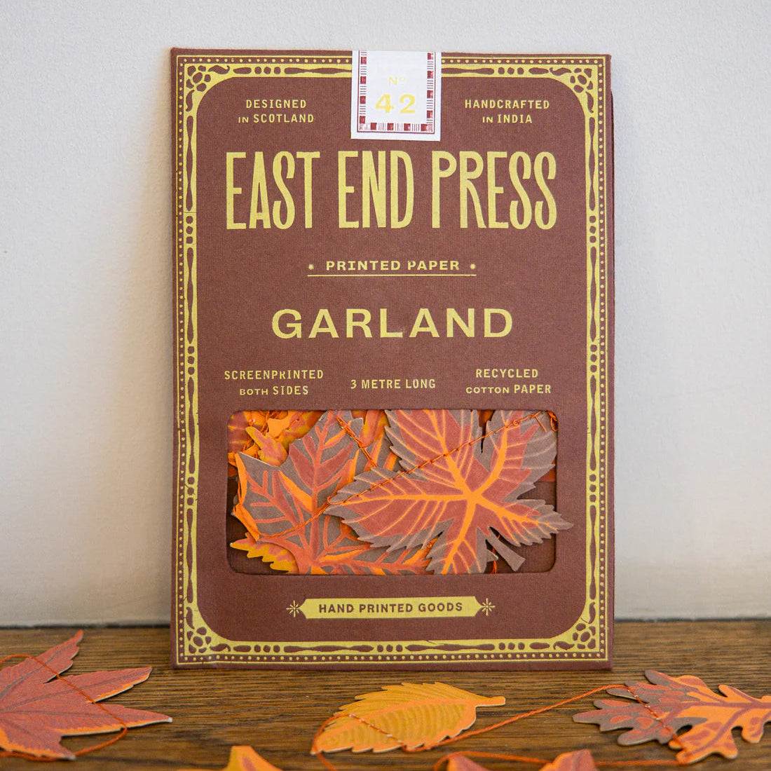Packaging of East End Press Garland printed paper with decorative leaves on a wooden surface.