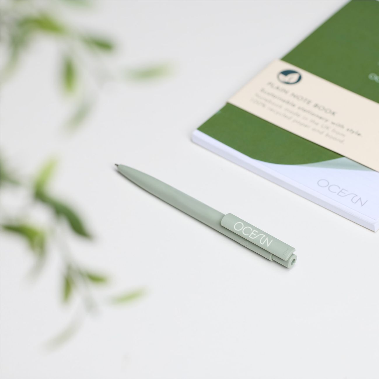 Lifestyle of a green pen lying in front of a green notebook.