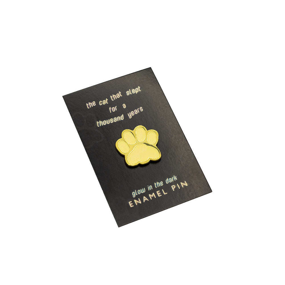Gold paw print enamel pin on a black card with text