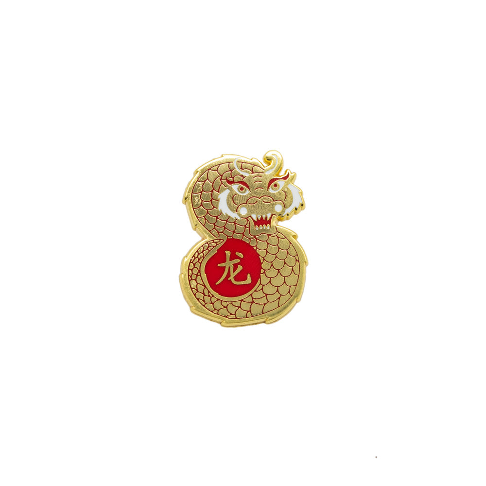 A gold pin in the shape of a dragon, white background