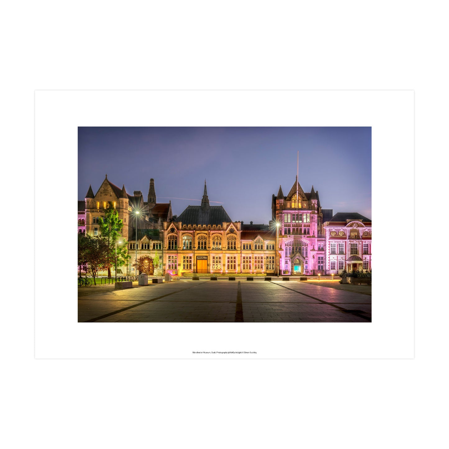 Photograph of the Manchester Museum's front at dusk with purple  and warm yellow lights across the facade.