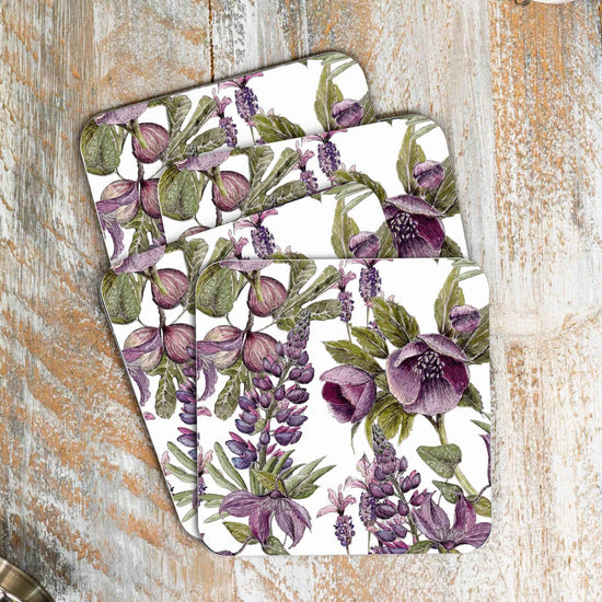 Stack of 4 coasters with purple and black floral design.  Photographed against wooden surface.
