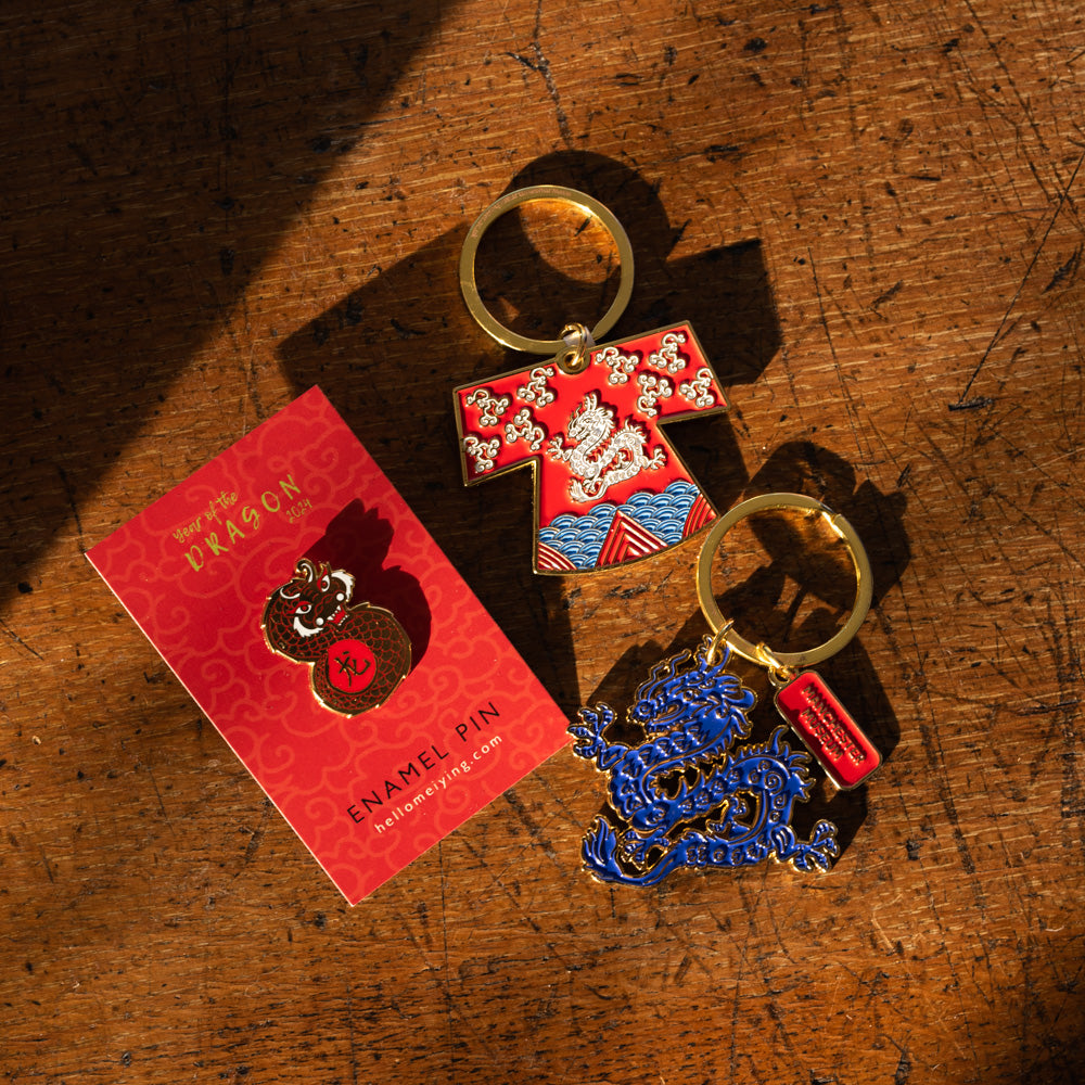 Lifestyle of dragon robe keyring and blue dragon keyring with the Lydia Meiying dragon enamel pin.