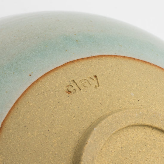 Detail of the underneath of a bowl. The detail is a close up of Clay Studio engraved into the clay.