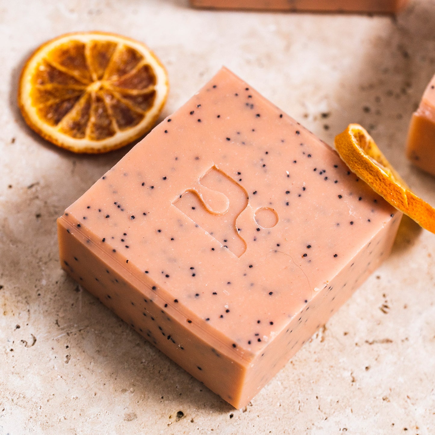 Pink speckled soap bar on a marbles surface with orange slices around it.