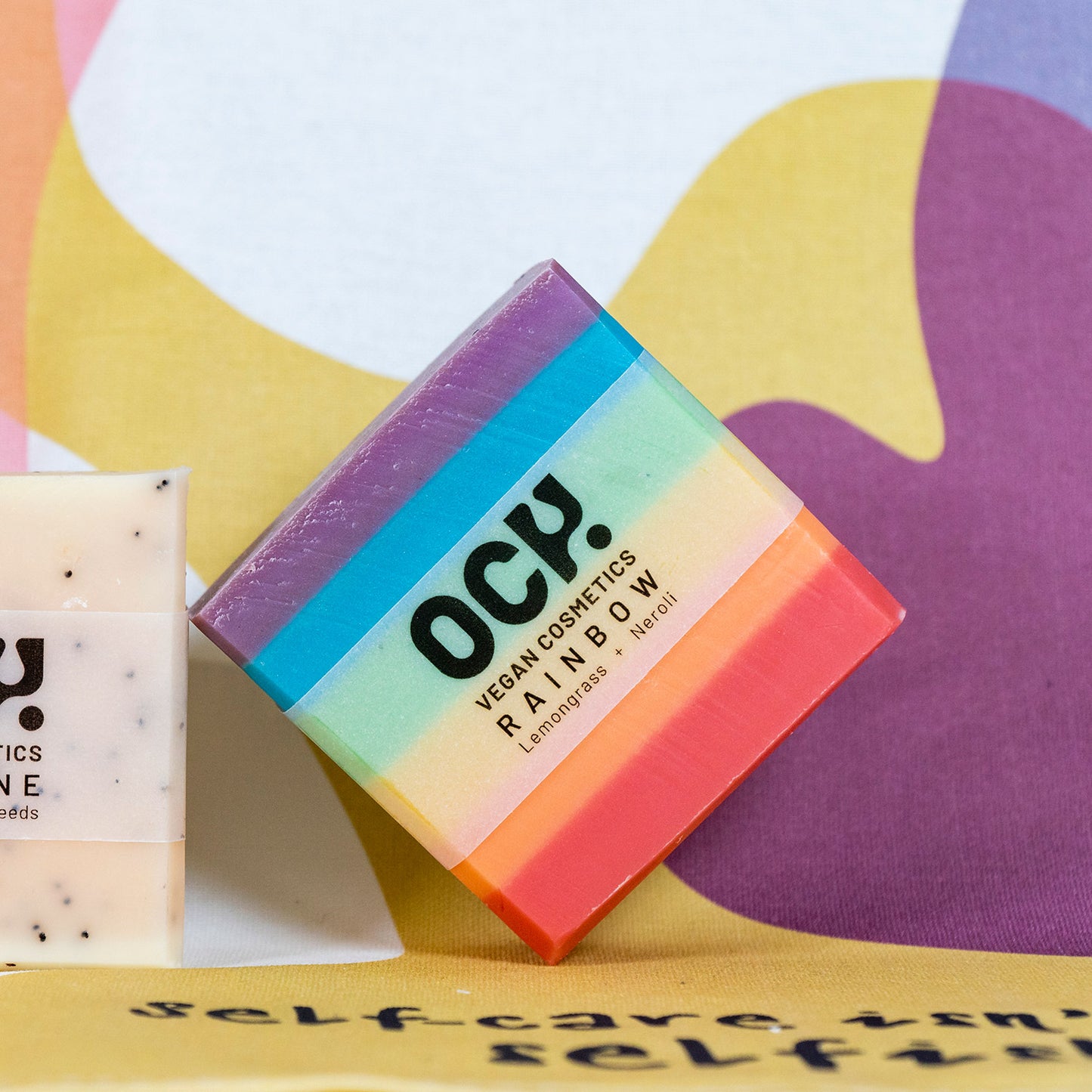 Rainbow coloured soap bar in front of colourful wall