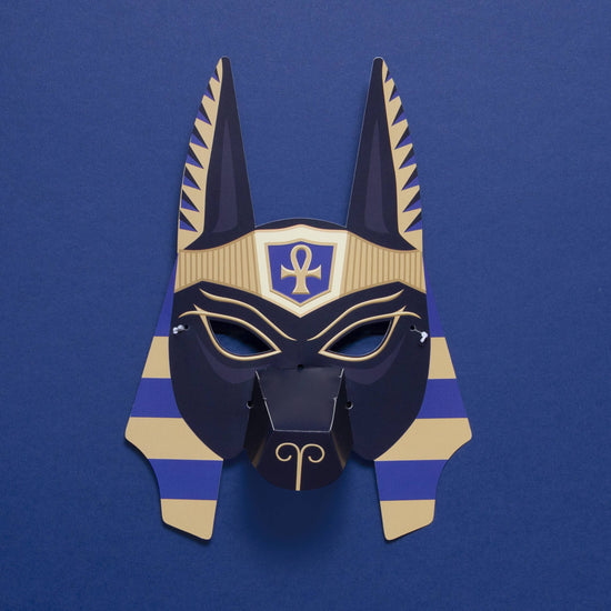 Anubis jackal mask with long pointy ears and seen against a blue background.