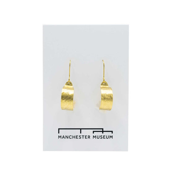Hammered brass hoop earrings on a white, museum branded backing card.