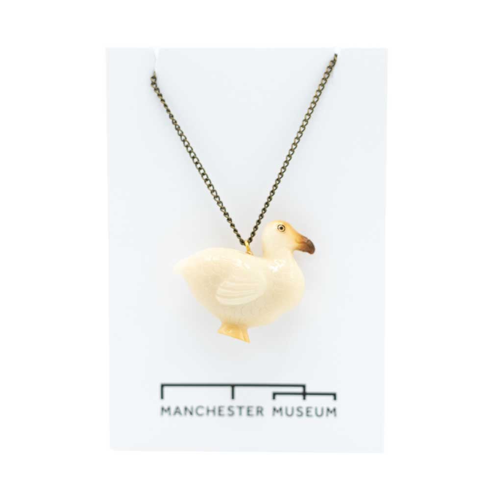Tagua carved dodo which is mostly white with some brown on the face and faint yelow on the feet. The necklace is draped onto the museum branded white card that is part of the sustainable packaging.