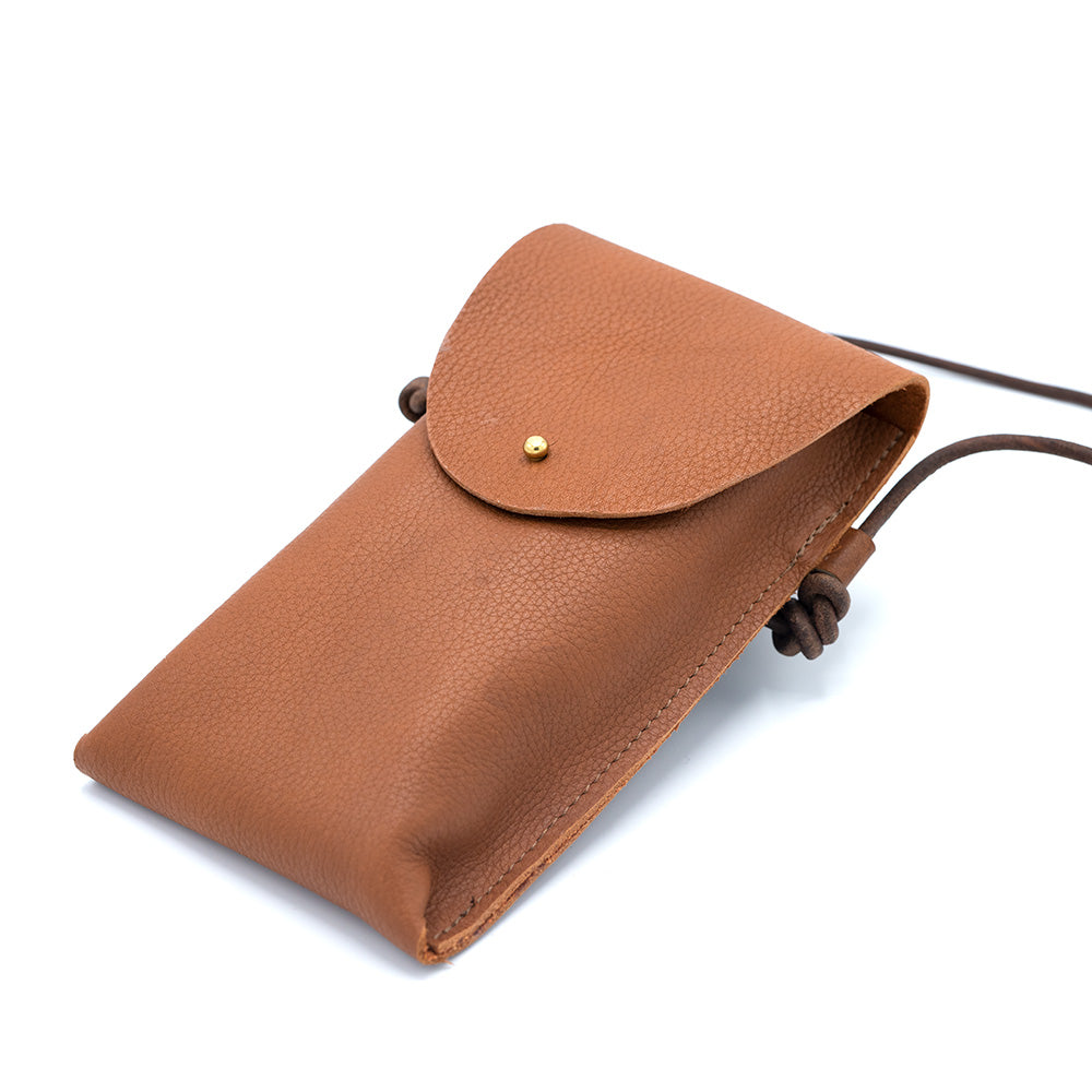 Brown leather phone bag lying on a white surface at a slight angle towards the camera.