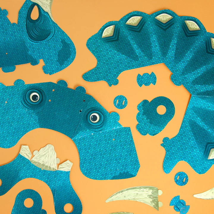 The pieces for the triceratops mask laid out flat with the turquoise side up.