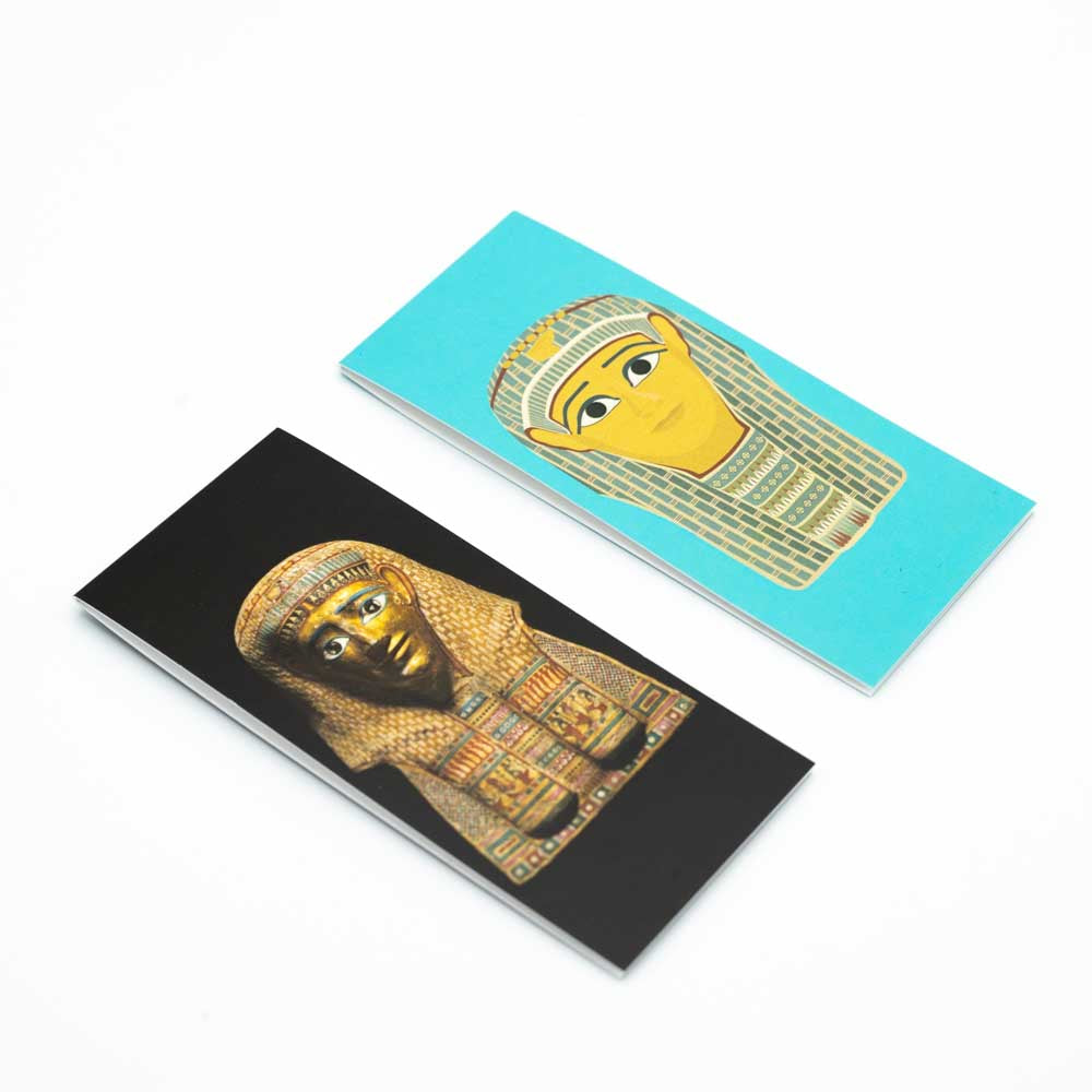 Black bookmark with photopgraph of Golden Mummies burial mask side by side with the turquoise burial mask illustration bookmark.