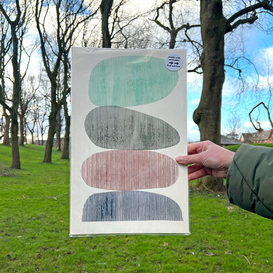 A person holding an a bstract print with pebble design in front of a park