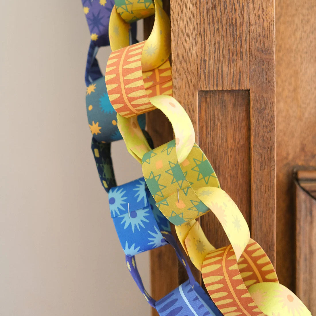 Colorful paper chains in yellow and blue hanging on a wooden mantelpiece.