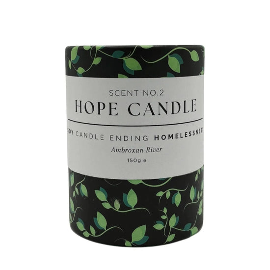 A black and green cylindrical candle container with text about the product, featuring a design of green leaves on a black background.