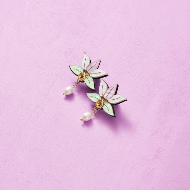 A pair of white pearl drop earrings with delicate floral-shaped charms.
