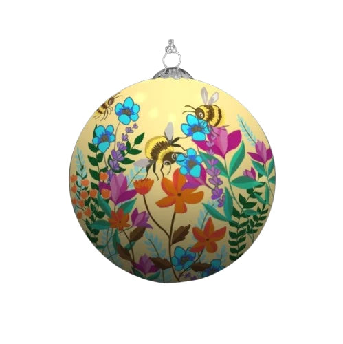 A colourful Christmas ornament depicting a vibrant garden scene with blooming flowers and buzzing bumblebees. The ornament has a cream background.