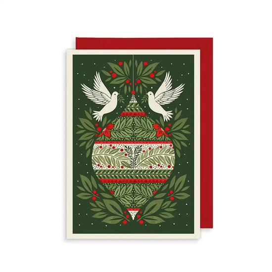 A Christmas card featuring a decorative bauble adorned with green leaves, red berries, and a red stripe. Two white doves fly on either side of the bauble against a green background.