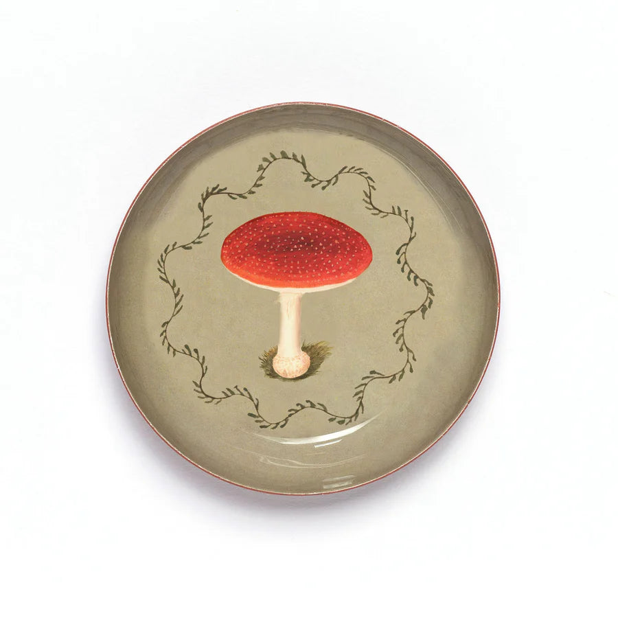 Round enamel tray with a fly agaric mushroom design on a beige background.