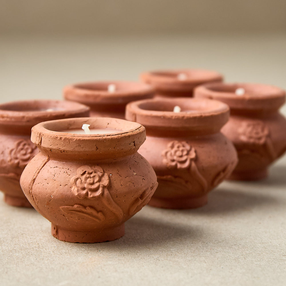 Terracotta mini candles with cream wax on a neutral background