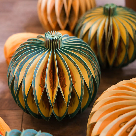 Decorative honeycomb paper gourds with unique on a wooden surface.
