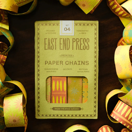 Packaging of East End Press paper chains on a dark surface with decorative ribbons.