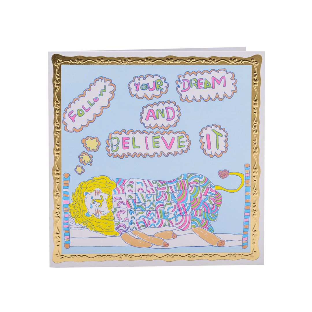 Square card with a pale blue background and a lying sleeping in a bed illustration. Text bubbles above the lion read: Follow your dream and believe it.