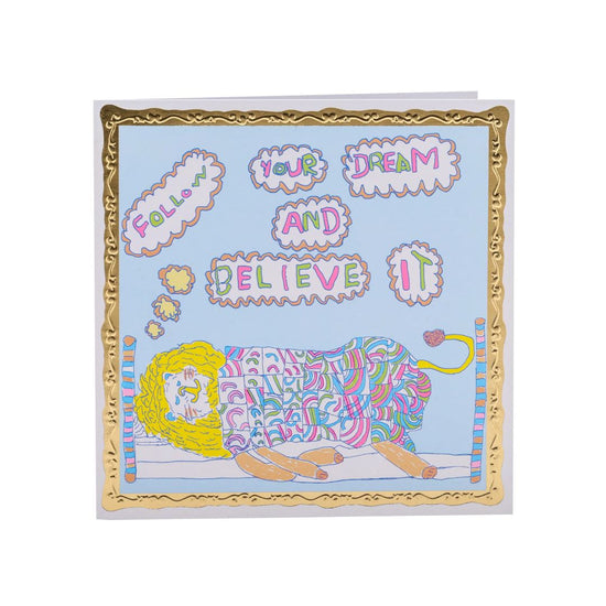 Square card with a pale blue background and a lying sleeping in a bed illustration. Text bubbles above the lion read: Follow your dream and believe it.