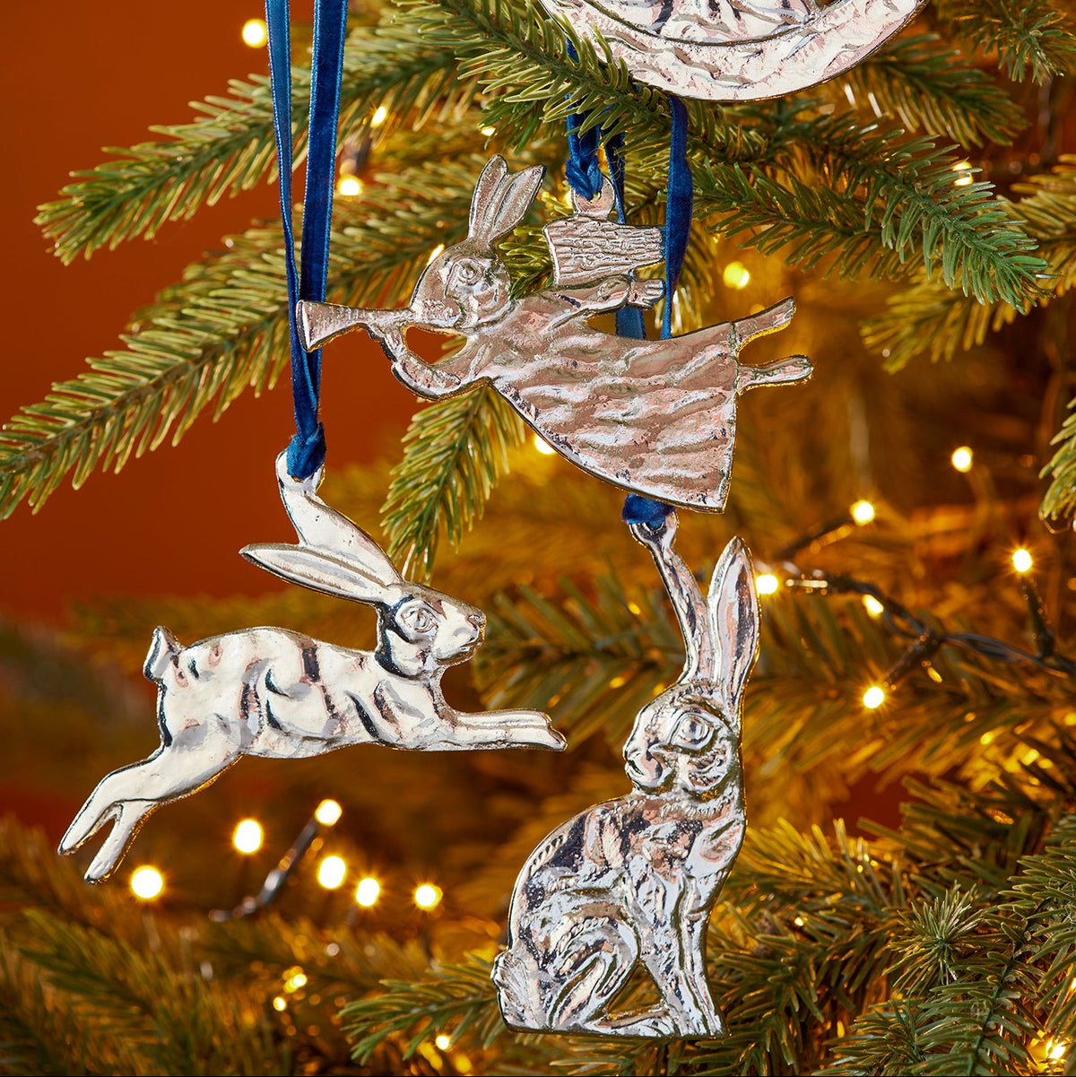 Silver sitting hare hanging decoration handcrafted from recycled aluminium and suspended from a blue velvet thread.