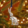 Silver sitting hare hanging decoration handcrafted from recycled aluminium and suspended from a blue velvet thread.