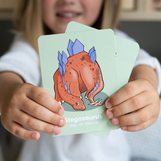 Lifestyle with a child holding two cards up in front of themselves with the card front towards the viewer.