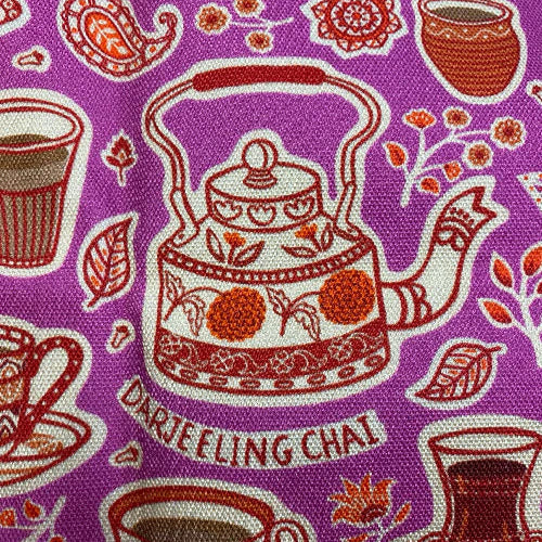Close up of tea towel with red tea-themed designs on a pink background.