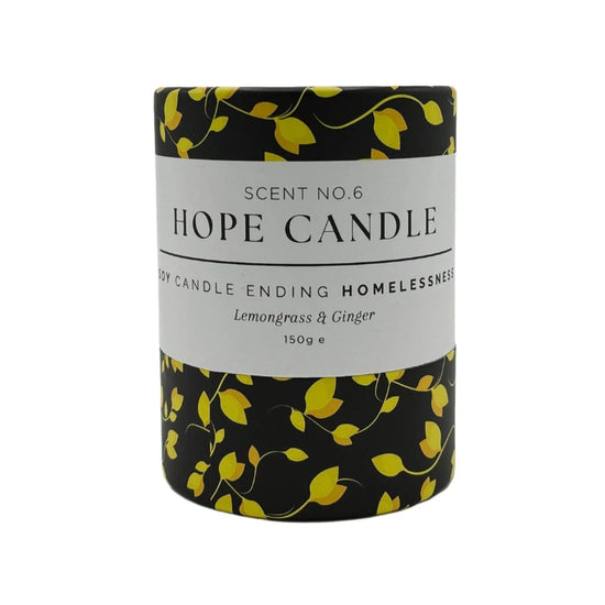 A black and yellow cylindrical candle container, featuring a design of yellow leaves on a black background.