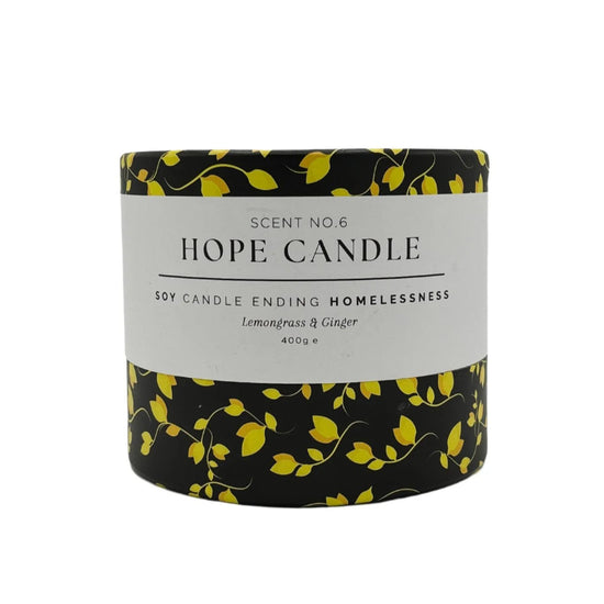 A black and yellow cylindrical candle container, featuring a design of yellow leaves on a black background.