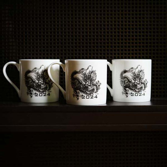 3 identical mugs with dragons on them photographed in front of a black background