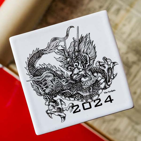 Square coaster with a dragon on it. 