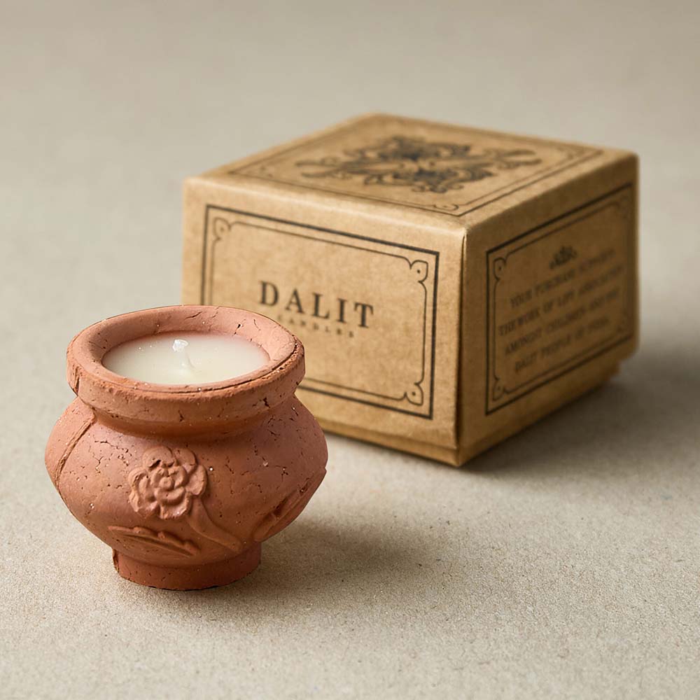 Terracotta candle with white wax next to a brown box labeled 'DALIT' on a beige background.