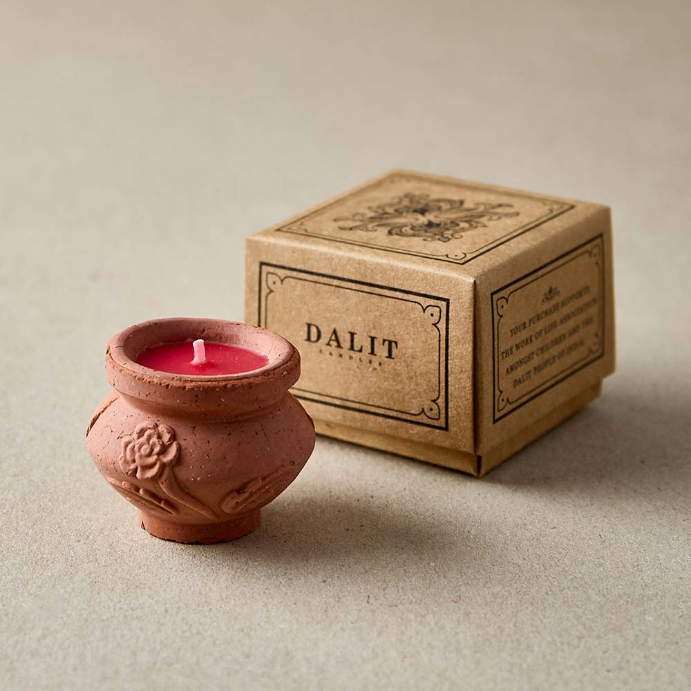Terracotta candle with red wax next to a 'DALIT' branded box on a beige background