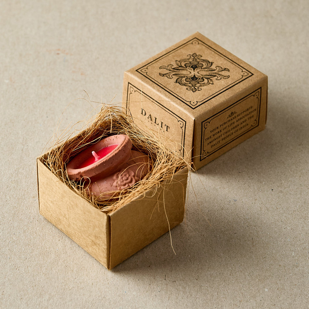 Mini terracotta candle with red wax in a decorative box with 'DALIT' branding on a beige background