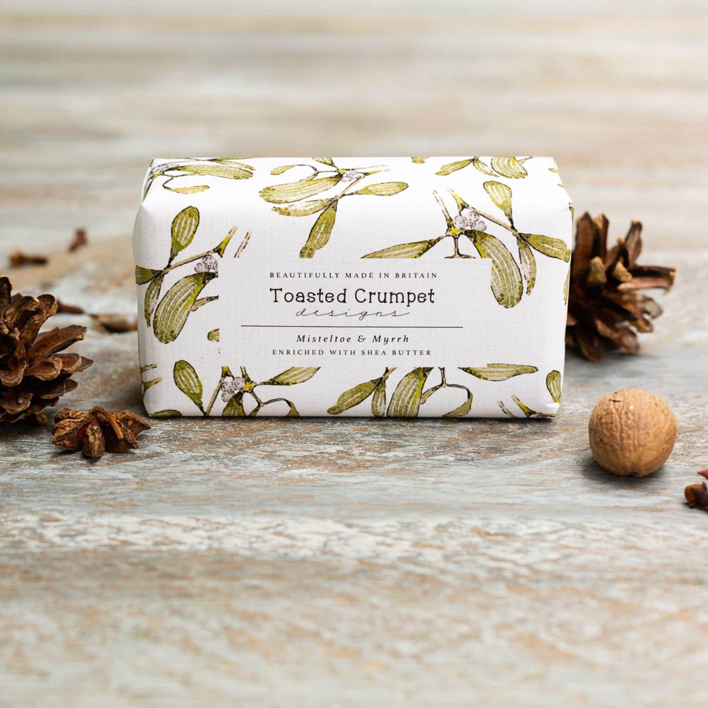 Soap bar with floral paper packaging placed on a wooden surface.