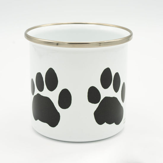 White mug with black paw prints and a silver rim on a white background