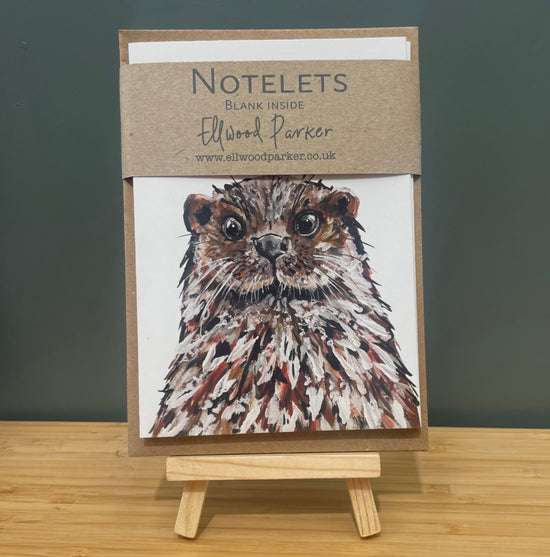Lifestyle photo of notelet pack with a brown belly band and sitting on a tiny easel.
