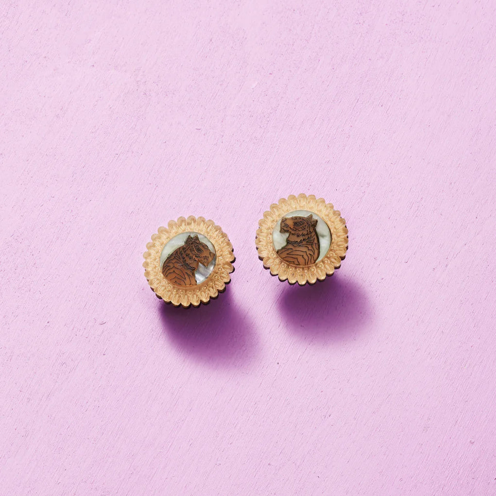 Pair of round earrings with a design on a pink background