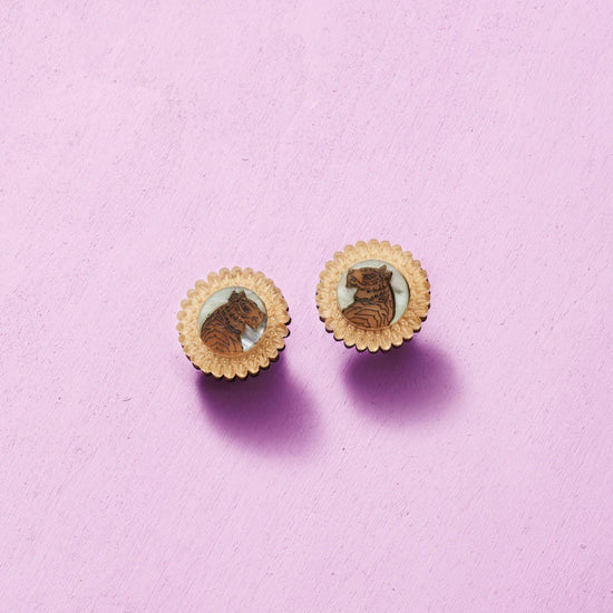 Pair of round earrings with a design on a pink background
