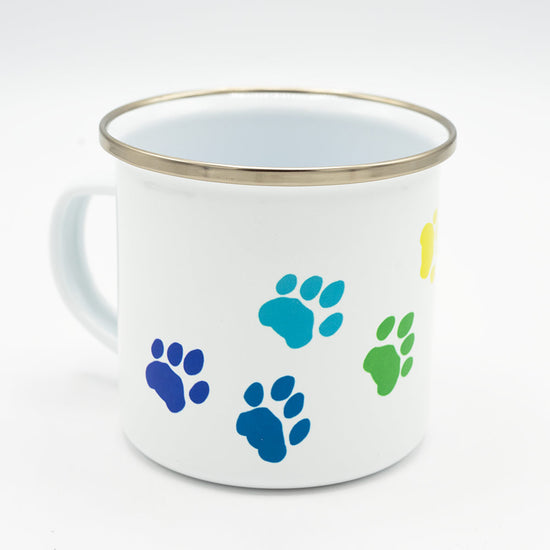 White mug with blue and green paw prints on a white background