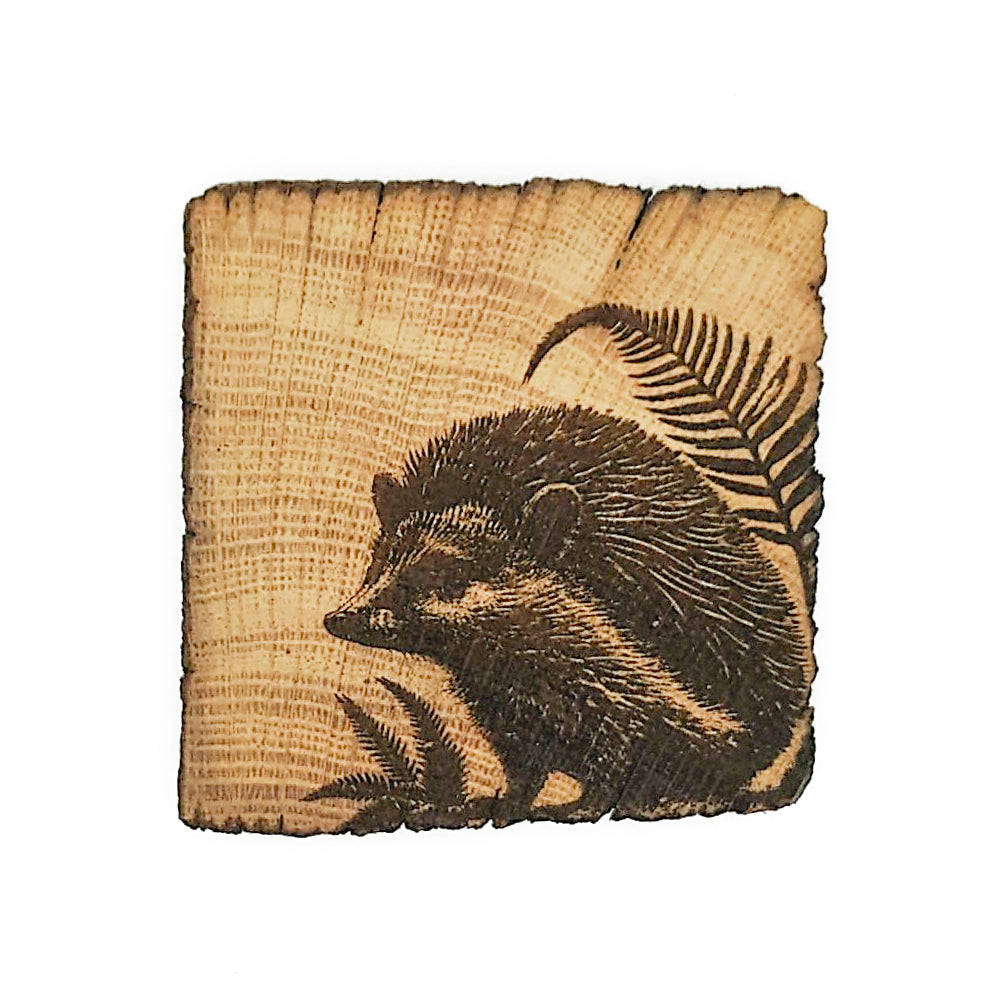 A wooden coaster with an engraving of a badger in the bottom right corner