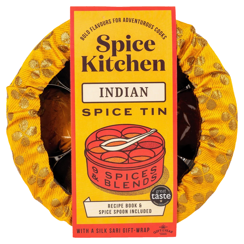 A Spice Kitchen Indian Spice Tin in its signature yellow and gold patterned silk sari wrap, with a tall yellow cardboard label in the center.
