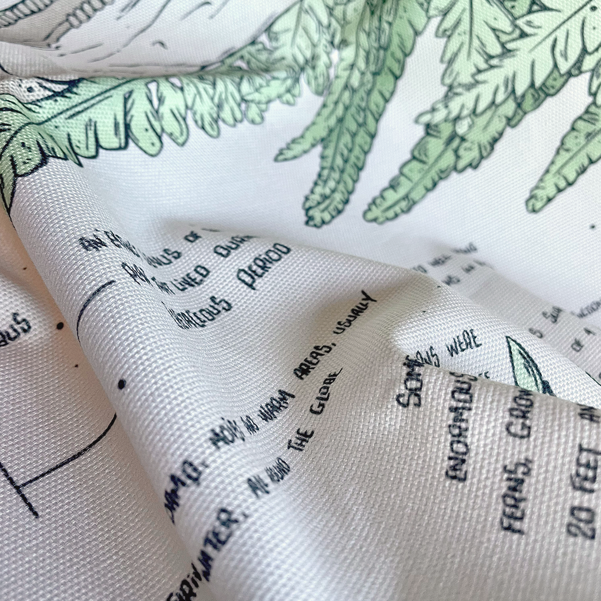 Tea towel close up with printed green leaves and text on a white background